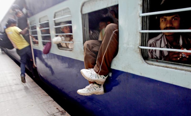 The feet of an Indian man hangs out from an overcrowded train at a railway station in New Delhi. Indian Railways plans to explore low-cost options for raising speeds to between 160kmph and 200 kmph on some routes like Delhi-Agra and Delhi-Chandigarh. Tsering Topgyal / AP Photo