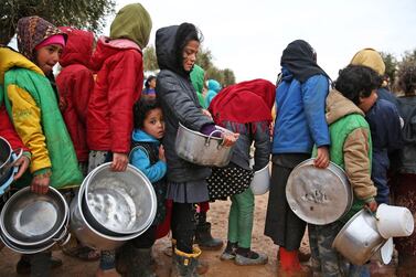 Syrian children queue to receive food distributed by aid workers at a makeshift camp for displaced people in northern Aleppo. Nazeer Al Khatib / AFP