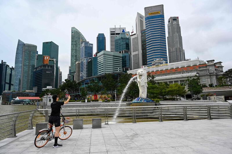 (FILES) In this file photo taken on January 4, 2021, a cyclist takes a photo in front of the Merlion statue in Singapore. Hong Kong and Singapore announced on April 26, 2021 plans to resurrect their scrapped coronavirus travel bubble with dedicated flights between the two cities starting on May 26. / AFP / Afp / Roslan RAHMAN
