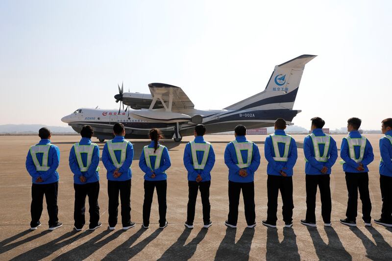 Members of ground staff stand in front of China's domestically developed AG600, the world's largest amphibious aircraft, after it lands on its maiden flight in Zhuhai, Guangdong province, China December 24, 2017. REUTERS/Stringer ATTENTION EDITORS - THIS PICTURE WAS PROVIDED BY A THIRD PARTY. CHINA OUT.