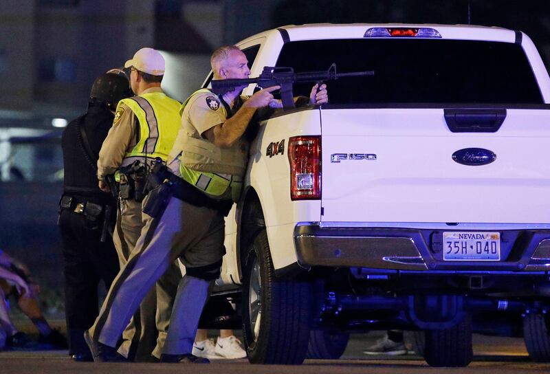 A police officer takes cover behind a truck at the scene of a shooting near the Mandalay Bay resort and casino on the Las Vegas Strip. John Locher / AP Photo