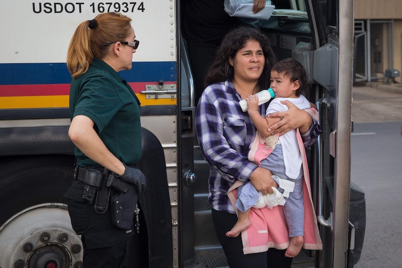 (FILES) In this file photo taken on June 17, 2018, a woman carries a baby as immigrants are dropped off at a bus station shortly after being released from detention through "catch and release" immigration policyin McAllen, Texas.  Hundreds of immigrant parents and children separated at the US-Mexico border were in limbo  Thursday as a court-set deadline for family reunification was set to expire. A federal judge in California, Dana Sabraw, has ordered that all eligible migrant families be brought back together by 6:00 pm (2200 GMT) on July 26, 2018. / AFP / Loren ELLIOTT
