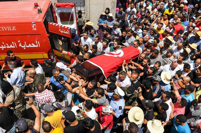 Mourners carry the coffin of killed Tunisian police officer Sgt. Arbi Guizani during a funerary procession in capital Tunis' northwestern suburb of Ettadhamen on July 9, 2018. Six members of Tunisia's security forces were killed on July 8 in a "terrorist attack" near the border with Algeria, the country's deadliest such incident in over two years. / AFP / FETHI BELAID
