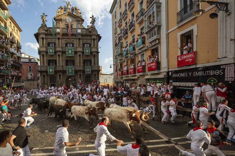 Revellers run with Cebada Gagos's fighting bulls before at Plaza Consistorial during the third day of the San Fermin Running of the Bulls festival in Pamplona, Spain. Getty