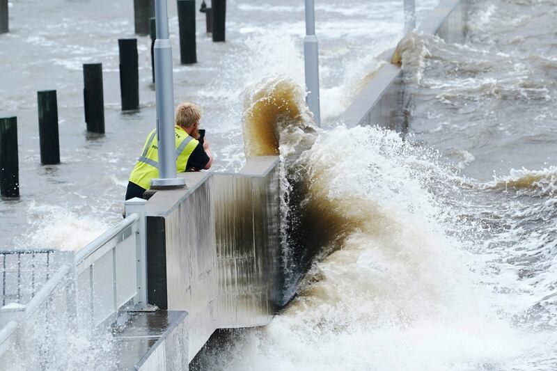 A utility worker photographs waves as they slam against a sea wall in Bay Saint Louis, Mississippi. AP