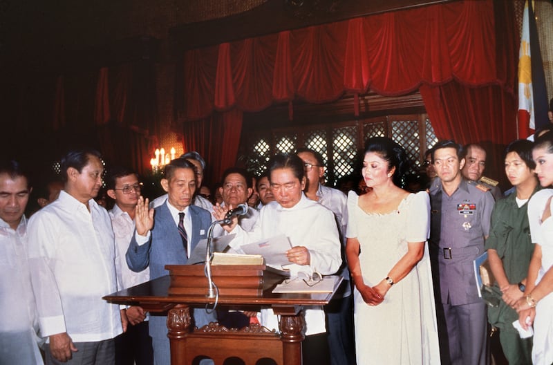 Marcos takes the oath of office on February 24, 1986, in Manila while his wife looks on. AFP