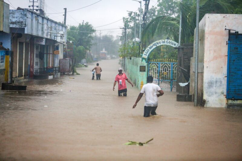People wade through flooded streets after Cyclone Biparjoy made landfall in the western state of Gujarat in India. EPA