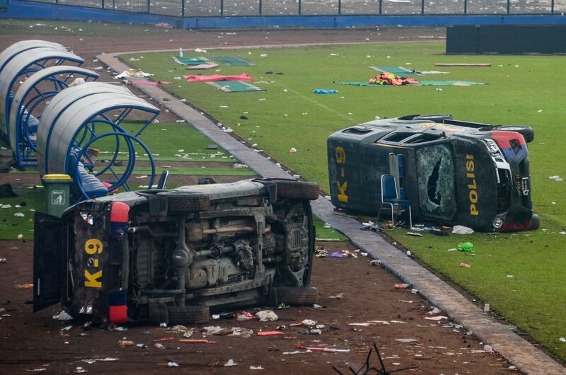 Damaged police vehicles lay on the pitch inside Kanjuruhan Stadium. EPA