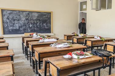 A school worker puts donated bouquets of flowers from the Kabul municipality on the empty desks of killed students as a tribute to their loss in Sayyid al-Shuhada school in the west Kabul, Afghanistan, 11 May 2021.  Following a terrorist attack on a girls' school in Kabul on 08 May 2021 that killed some 80 people and injured more than 100, the Afghan government declared 11 May as a national mourning day.   EPA / HEDAYATULLAH AMID