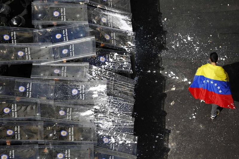 A man draped with a Venezuelan flag protests against the government of Venezuela’s president Nicolas Maduro in front of a riot police line in Caracas on February 12, 2014. Jorge Silva / Reuters