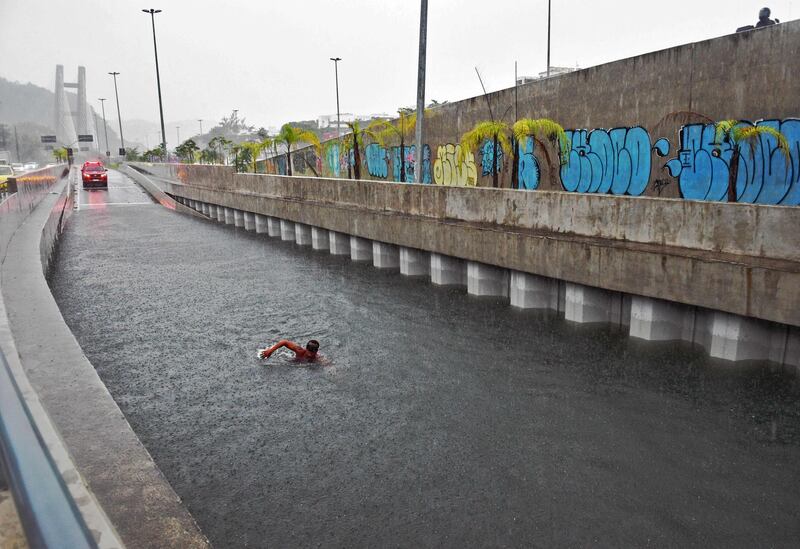 A firefighter of the underwater unit dives to inspect a submerged car at a road tunnel after heavy rains in Rio de Janeiro, Brazil. AFP