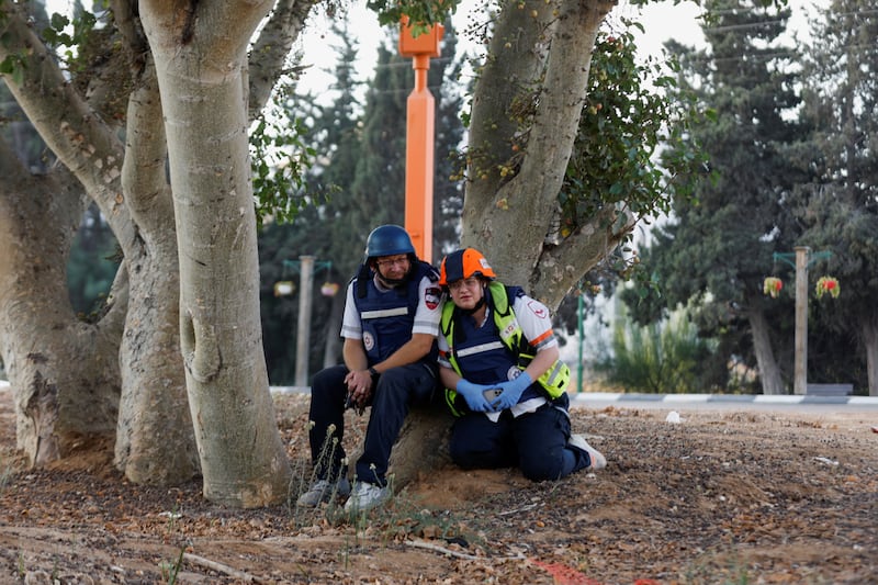 Israeli emergency personnel sit under a tree in Ashkelon after rockets were launched into Israel from the Gaza Strip. Reuters