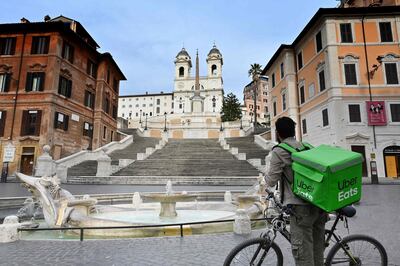 An Uber Eats delivery man stands by hte Spanish Steps at a deserted Piazza di Spagna in central Rome on March 12, 2020, as Italy shut all stores except for pharmacies and food shops in a desperate bid to halt the spread of a coronavirus. / AFP / Alberto PIZZOLI
