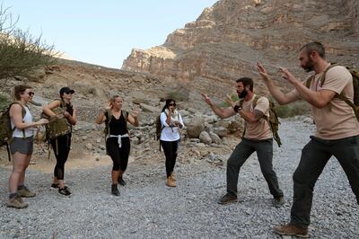 Martin Norton, lead instructor of the Bear Grylls Survival Academy, second right, explains to adventures how to react if they face a wild animal during a trial survival course at Jebel Jais, about 30 kms north east of Ras al-Khaimah, United Arab Emirates, Thursday, Oct. 8, 2020.  Ras al-Khaimah has partnered with the adventurer Bear Grylls to offer a new outdoor adventure camp on Jebel Jais, a mountain that has the highest point in the oil-rich United Arab Emirates. (AP Photo/Kamran Jebreili)