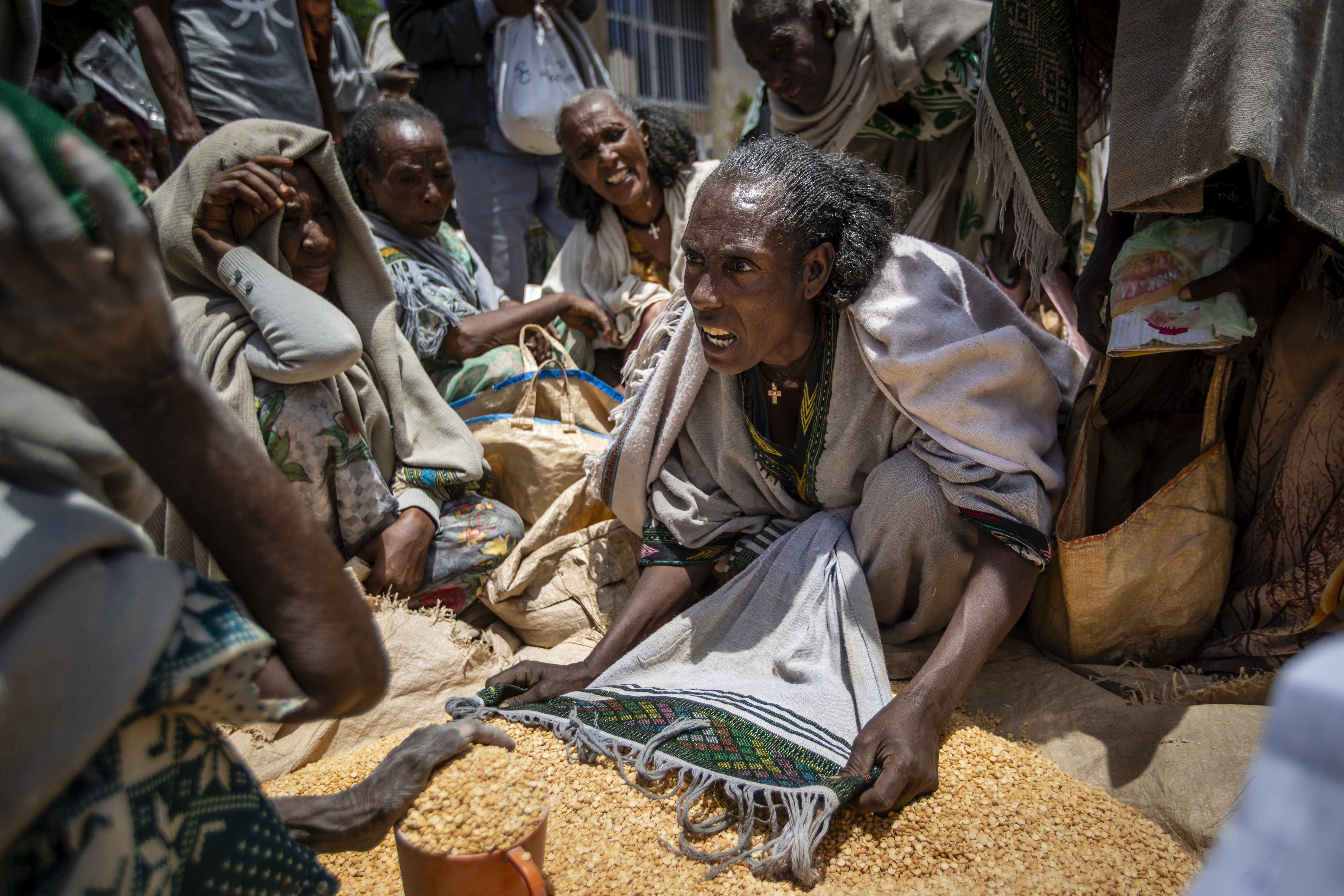 A woman argues over the allocation of split peas in Tigray. The fighting has left nine million people in Ethiopia requiring food aid, says the UN. AP