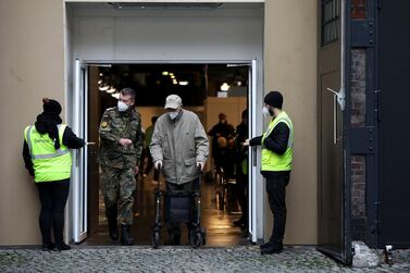 A soldier escorts an elderly visitor from a Covid-19 vaccination clinic in Berlin. Bloomberg