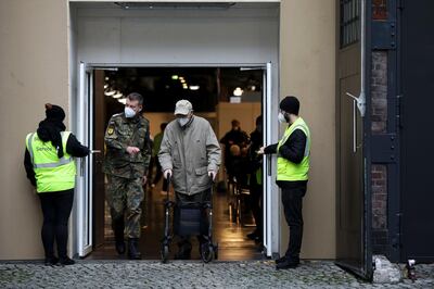 A soldier escorts an elderly visitor as they exit a Covid-19 vaccination site at Berlin Arena in Berlin, Germany, on Monday, Jan. 4, 2021. Germany is poised to extend stricter lockdown measures beyond Jan. 10 amid criticism over alleged failures in the government’s fledgling vaccination program.  Photographer: Liesa Johannssen-Koppitz/Bloomberg
