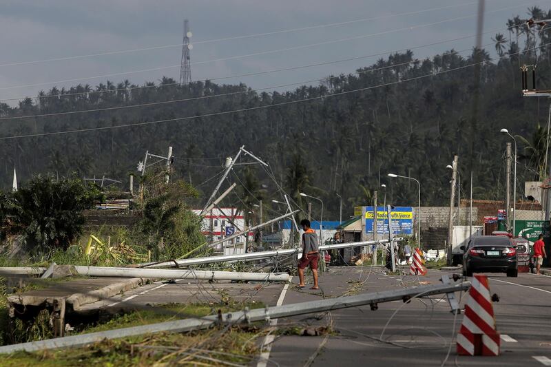 A man walks past electric poles lying on the main highway after Typhoon Kammuri hit Camalig town, Philippines. Reuters