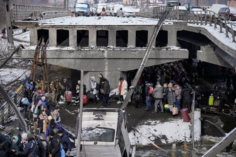 Ukrainians pass a damaged bridge as they flee from Irpin. AP