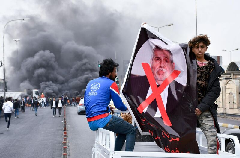 Iraqi demonstrators lift a poster of premier-designate Mohammad Allawi with the mention "rejected" during an anti-government protest in the southern city of Nasiriyah.  AFP