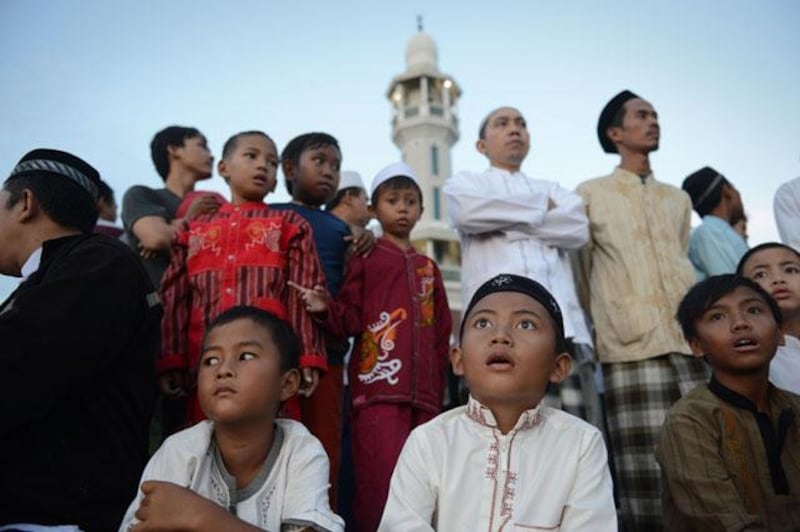 Indonesian children and elder Muslim men prepare to sight the new moon from the rooftop of the Al-Hidayah Basmol mosque in Jakarta on July 8, 2013 in preparation for the beginning of the Muslim holy fasting month of Ramadan. The start of the holy month of Ramadan, when the faithful abstain from eating from dawn to sunset, is determined by the sighting of the new moon. AFP PHOTO / ROMEO GACAD

