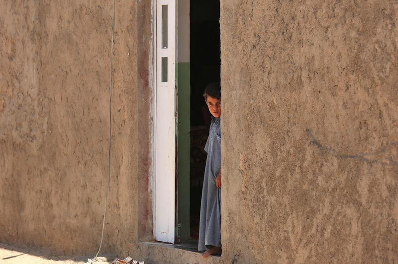 A boy stands in the doorway at his house in Al Sahl.