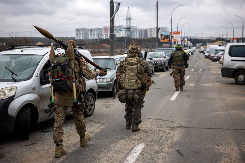 Ukrainian soldiers carry rocket-propelled grenades and sniper rifles as they walk towards the city of Irpin, north-west of Kyiv. AFP
