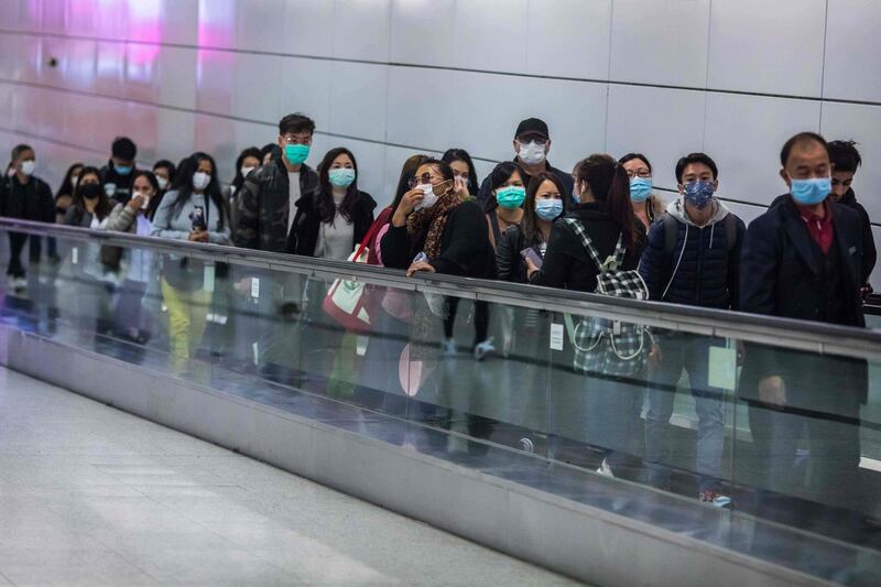 People in Hong Kong wearing facemasks as a preventative measure, following a coronavirus outbreak in the Chinese city of Wuhan, ride a travelator inside a train station on the second day of the Lunar New Year of the Rat.  AFP