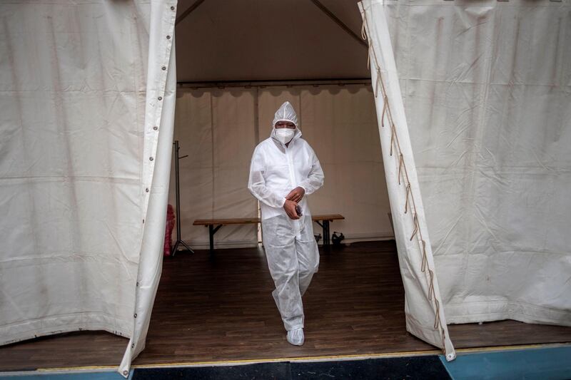 TOPSHOT - A healthcare worker wearing personal protective equipment (PPE) makes his way out of a temporary ward dedicated to the treatment of possible COVID-19 coronavirus patients at the Nasrec Field Hospital in Soweto, on January 25, 2021. / AFP / Michele Spatari
