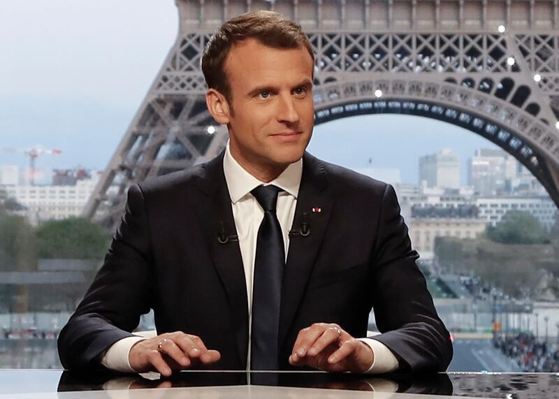 French President Emmanuel Macron (C) poses on the TV set before an interview with RMC-BFM and Mediapart French journalists at the Theatre national de Chaillot in Paris, on April 15, 2018, after United States, Britain and France decided to launch air strikes in Syria in response to a suspected chemical weapons attack. / AFP PHOTO / AFP PHOTO AND POOL / FRANCOIS GUILLOT