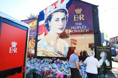 FILE - A couple pay their respect at a picture of Queen Elizabeth II on the Loyalist Shankill Road in west Belfast, Sept.  10, 2022.  Britain's longest-reigning monarch and a rock of stability across much of a turbulent century, died Sept.  8, 2022.  (AP Photo / Peter Morrison, File)