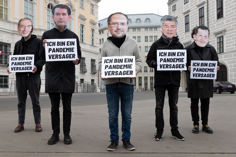 Protesters at the federal chancellery building in Vienna wear masks depicting political leaders. They hold signs that read 'I am a pandemic failure.' AP