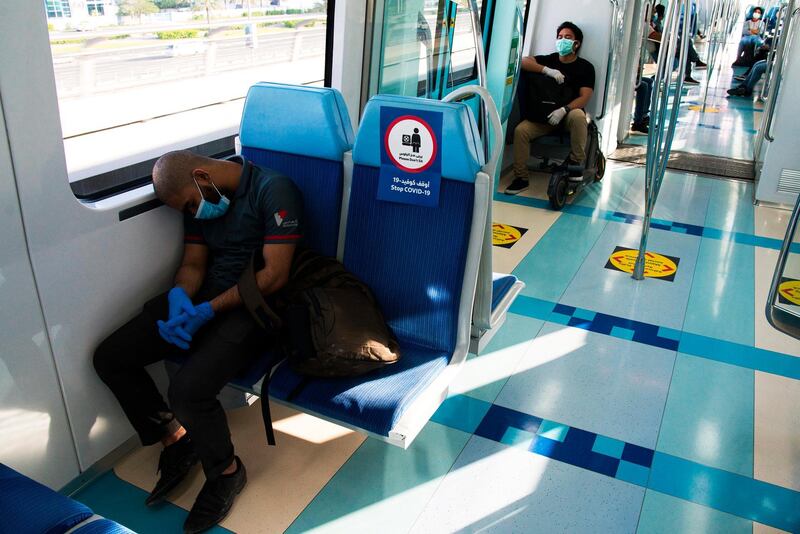 A commuter wearing a mask and disposable gloves due to the coronavirus pandemic sleeps aboard the driverless Metro in Dubai. AP Photo