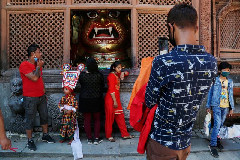 A Nepalese girl stands for a photograph in front of an idol of Swet Bhairav statue while participating in a procession to mark 'Gai Jatra', or cow festival, in Kathmandu, Nepal. AP Photo