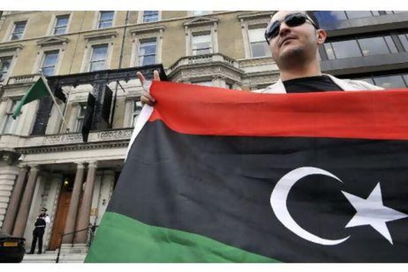 A man holding the flag of the Libyan rebels stands outside the Libyan embassy in London yesterday after Britain recognised the National Transitional Council as the country's sole governmental authority, and expelled diplomats appointed by the Qaddafi regime. Andy Rain / EPA/