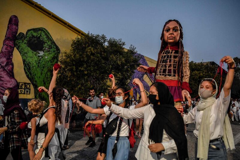 Young refugee women perform as Little Amal is paraded through the streets of Athens. The refugee child puppet is intended to embody the message, 'Don’t forget about us.' AFP