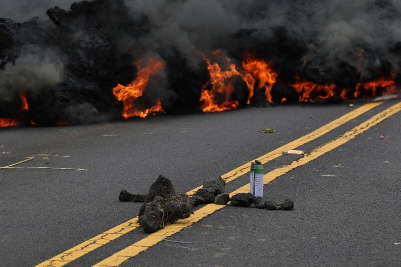 Lava burns across a road as an offering to the volcano goddess lies in the foreground in the Leilani Estates subdivision near Pahoa, Hawaii. Caleb Jones / AP Photo