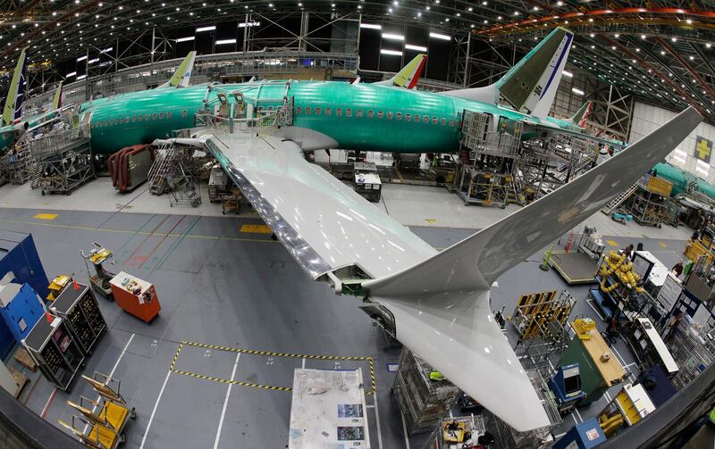 FILE- In this March 27, 2019, file photo taken with a fish-eye lens, a Boeing 737 MAX 8 airplane sits on the assembly line during a brief media tour in Boeing's 737 assembly facility in Renton, Wash. Boeing is cutting production of its grounded Max airliner this month to focus on fixing flight-control software and getting the planes back in the air. The company said Friday, April 5, that starting in mid-April it will cut production of the 737 Max from 52 to 42 planes per month. (AP Photo/Ted S. Warren, File)