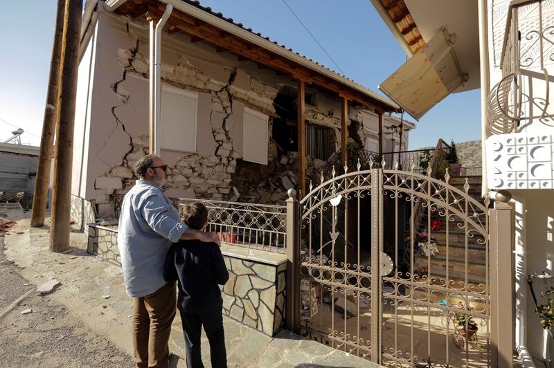 People look at a damaged house following an earthquake in the village of Damasi. Reuters