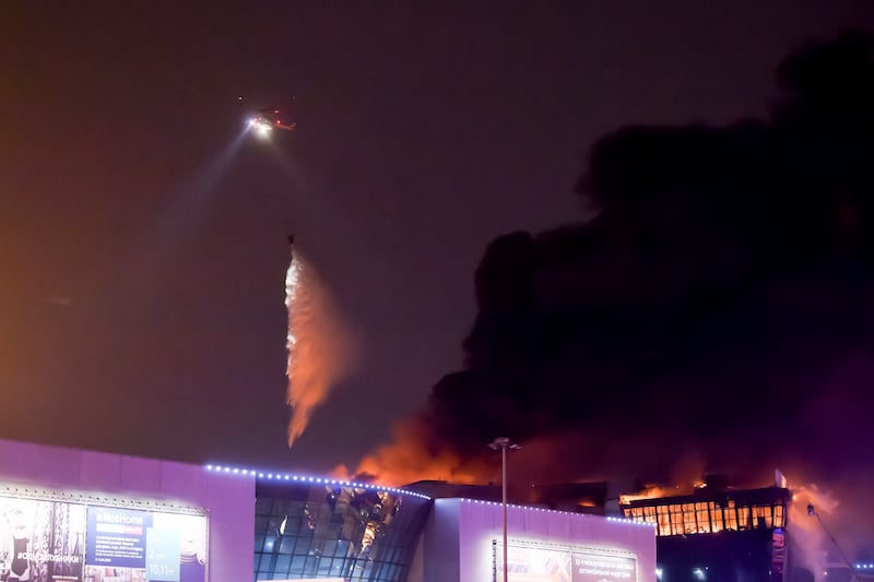 A firefighting helicopter douses flames at Crocus City Hall. AP