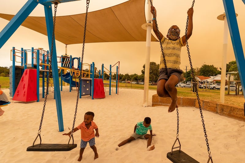 Residents from Ellenbrook play on swings at the Brown Park Recreation Complex evacuation centre in Perth. EPA