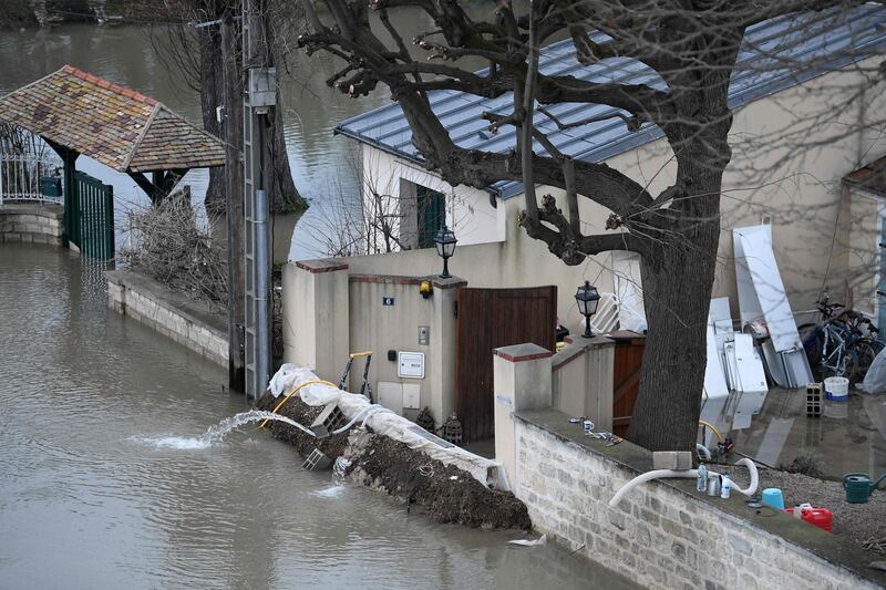A barrier erected in front of a house to block floodwater from the Seine river, left, in Bougival, west of Paris. Stephane De Sakutin / AFP