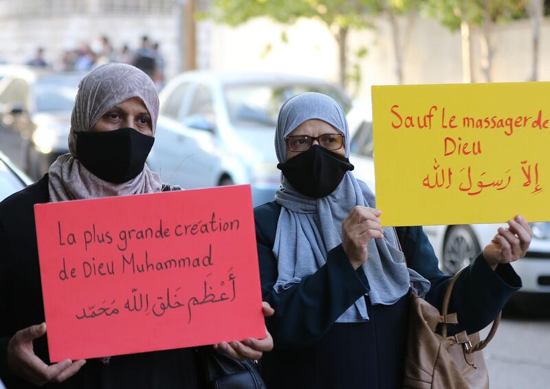 Muslim women hold up placards during a protest outside the French embassy in the  Jordanian capital Amman against French President Emmanuel Macron's defence of cartoons depicting the Prophet Mohammed. Slogan in French and Arabic on yellow placard reads: "Anyone but the prophet". Calls to boycott French goods are growing in the Arab world and beyond, after Macron criticised Islamists and vowed not to "give up cartoons" depicting the Prophet Mohammed in recent comments that came in response to the beheading of a teacher, Samuel Paty, outside his school in a suburb outside Paris earlier this month, after he had shown cartoons of the Prophet Mohammed during a class he was leading on free speech. AFP