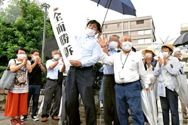 A group of supporters for plaintiffs celebrate, holding a banner which reads "Overall victory" outside the Hiroshima district court in Hiroshima. AP