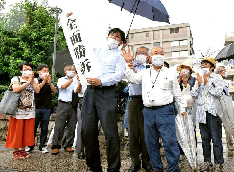 A group of supporters for plaintiffs celebrate, holding a banner which reads "Overall victory" outside the Hiroshima district court in Hiroshima, western Japan, Wednesday, July 29, 2020.  A court has recognized people exposed to radioactive â€œblack rainâ€ that fell after the U.S. atomic attack on Hiroshima as atomic bomb survivors, ordering the government to provide the same medical benefits it gives other survivors. (Kyodo News via AP)