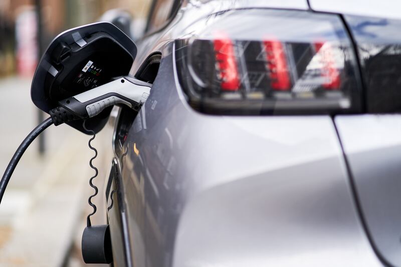 A Peugeot electric car plugged into a EV charging point. PA