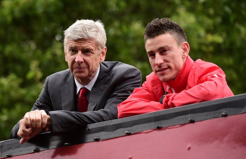 Arsenal's French manager Arsene Wenger, left, and Arsenal's French defender Laurent Koscielny look out from an open top bus during the Arsenal victory parade in London on May 31, 2015, following their win in the English FA Cup final. AFP PHOTO / LEON NEAL