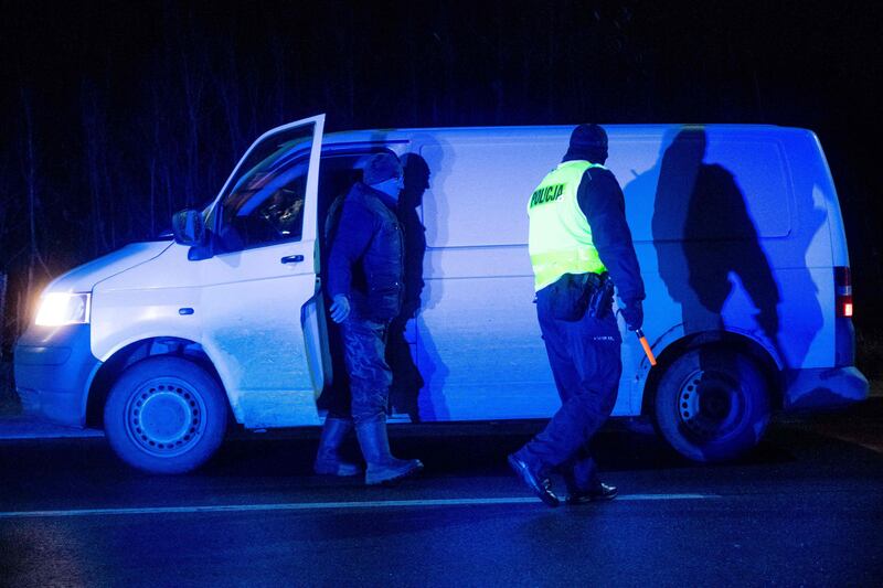 A police officer checks a vehicle entering the state-of-emergency area at a checkpoint near the village of Narew, eastern Poland. AFP