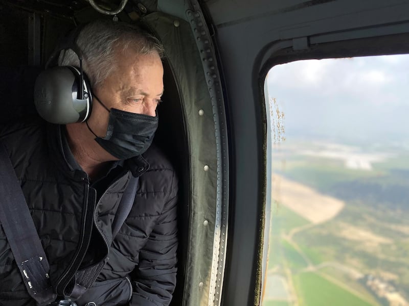 Israeli Defence Minister Benny Gantz wears a face mask as he looks out from the window of a helicopter during a tour of the Gaza border area, southern Israel March 2, 2021. REUTERS/Dan Williams