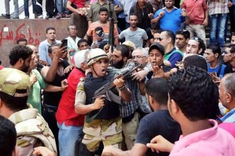 An army officer points his weapon at the crowd as he escorts a man out of Al Fath mosque where Islamist supporters of ousted president Mohammed Morsi were taking shelter on Saturday. Mohammed El Shahed / AFP